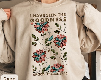 Puede incluir: Una sudadera beige con un diseño floral y el texto "I have seen the goodness of God Psalms 27:13".