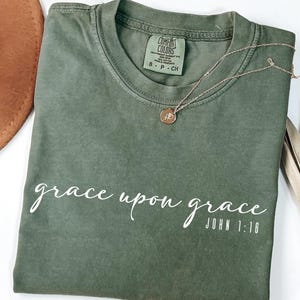 May include: A green t-shirt with the text "grace upon grace JOHN 1:16" in white lettering.