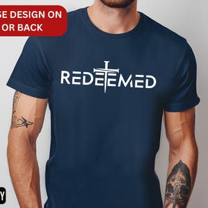 May include: A navy blue t-shirt with a white cross and the word "REDEEMED" printed on the front.
