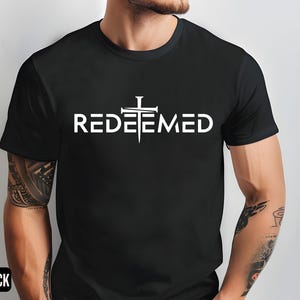 May include: A black t-shirt with a white graphic of a cross with nails and the word "REDEEMED" underneath.