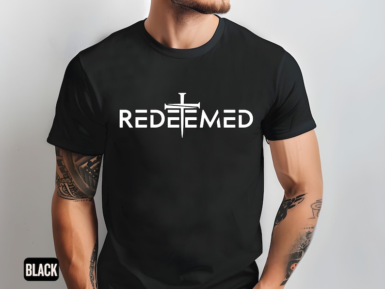 May include: A black t-shirt with a white graphic of a cross with nails and the word "REDEEMED" underneath.