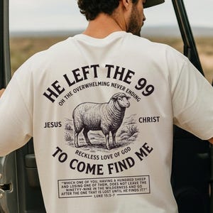 May include: Off-white t-shirt featuring a sheep illustration and text. The text reads "HE LEFT THE 99" and "TO COME FIND ME", along with a quote from Luke 15:3-7. The shirt is a simple, casual garment.