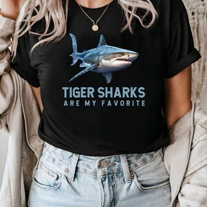 May include: A black t-shirt with a blue tiger shark graphic and the text "Tiger Sharks Are My Favorite".