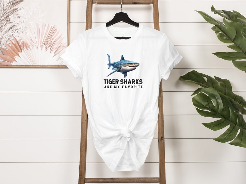 May include: White t-shirt with a blue tiger shark graphic and the text "Tiger Sharks Are My Favorite".
