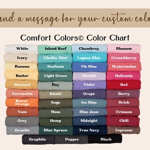 May include: A Comfort Colors color chart displaying a grid of folded fabric swatches in various shades including white, ivory, banana, butter, mustard, terracotta, burnt orange, yam, grey, granite, island reef, chalky mint, seafoam, light green, bay, khaki, sage, moss, hemp, blue spruce, chambray, lagoon blue, flo blue, orchid, violet, grape, ice blue, blue jean, midnight, true navy, blossom, crunchberry, watermelon, heliconia, red, berry, brick, crimson, chili, espresso, graphite, pepper, and black.