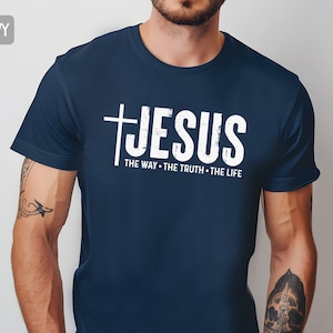 May include: A navy blue t-shirt with a white distressed graphic of a cross and the word "JESUS" with the text "THE WAY - THE TRUTH - THE LIFE" underneath.
