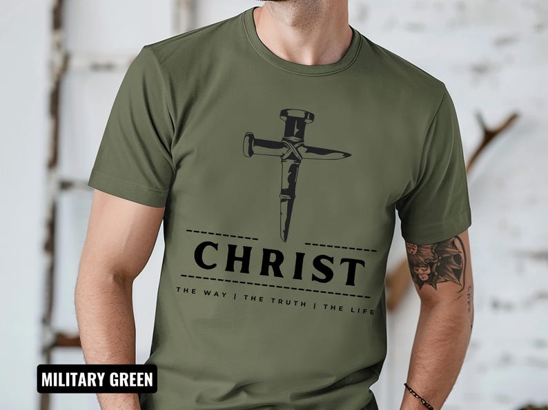 May include: A military green t-shirt with a graphic of a nail hammered into a cross. The text "CHRIST THE WAY | THE TRUTH | THE LIFE" is printed below the graphic.