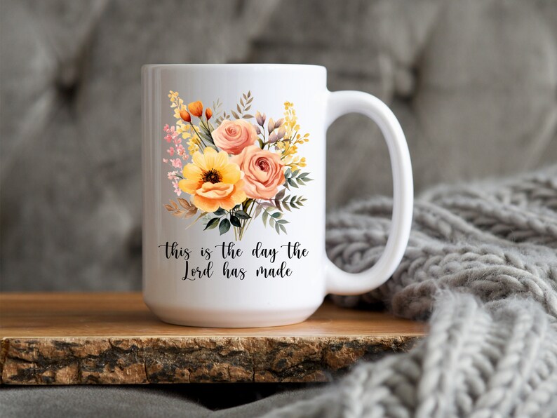 Puede incluir: Taza de cer&aacute;mica blanca con un dise&ntilde;o floral con flores amarillas y naranjas. La taza tiene una inscripci&oacute;n negra que dice "This is the day the Lord has made."