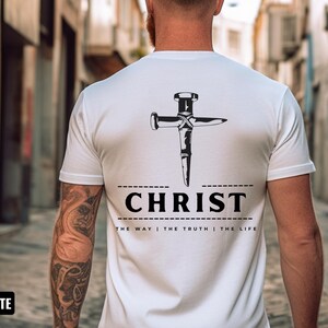 May include: White t-shirt with a black graphic of a nail hammered into a cross. The text "CHRIST" is below the graphic, and the text "THE WAY | THE TRUTH | THE LIFE" is below that.