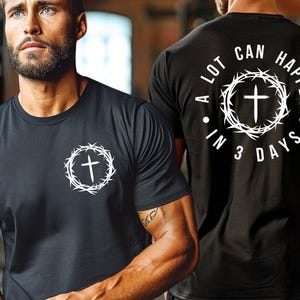 May include: Black t-shirt with a white crown of thorns and cross design on the front. The back of the shirt has the text "A LOT CAN HAPPEN IN 3 DAYS" with a white crown of thorns and cross design.