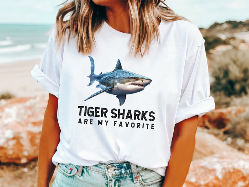 May include: White t-shirt with a graphic of a tiger shark and the text "Tiger Sharks Are My Favorite".