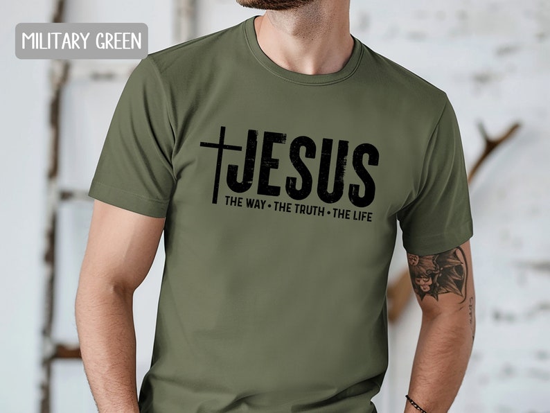 May include: A military green t-shirt with a black graphic that says "JESUS THE WAY. THE TRUTH. THE LIFE."