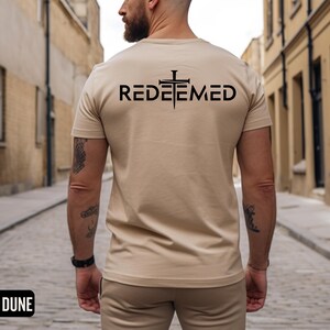 May include: A beige t-shirt with a black cross and the word "REDEEMED" printed on the back.