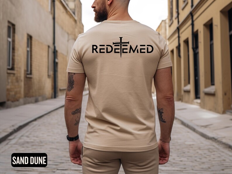 May include: A beige t-shirt with a black cross and the word "REDEEMED" printed on the back.