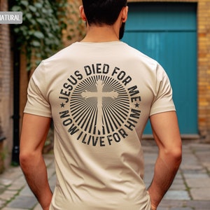 May include: A beige t-shirt with a black graphic on the back. The graphic is a circle with a cross in the center and the text "Jesus Died For Me * Now I Live For Him".