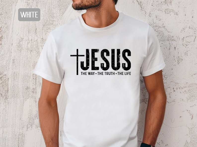 May include: White t-shirt with a black graphic of a cross and the word "JESUS" with the text "THE WAY - THE TRUTH - THE LIFE" underneath.