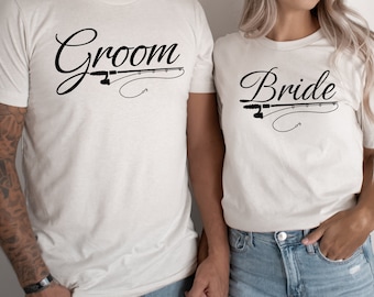 May include: A couple wearing white t-shirts with the words "Groom" and "Bride" printed on them. The shirts feature a fishing rod and hook design.