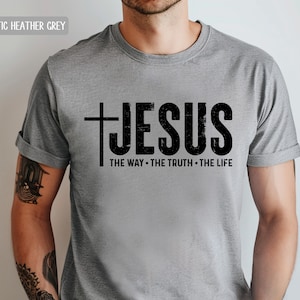 May include: A heather grey t-shirt with a black cross and the word "JESUS" printed on the front. The text below reads "THE WAY - THE TRUTH - THE LIFE".