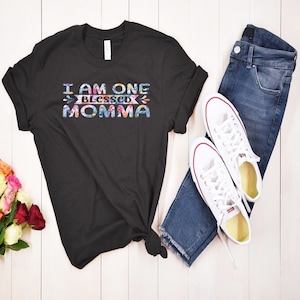 May include: Black t-shirt with the text "I am one blessed momma" in colorful letters with a floral design.