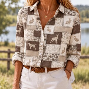 May include: A long-sleeved button-down shirt featuring a patchwork pattern of brown and beige squares. The design includes illustrations of rabbits, deer, ducks, and dogs interspersed with camouflage-style textures. The shirt has a collar and cuffs.