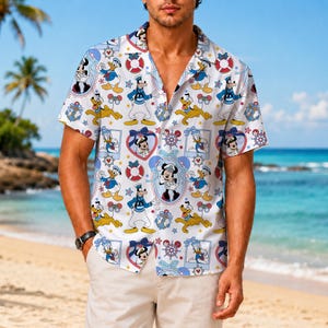 Op de afbeelding: Een overhemd met korte mouwen en knoopsluiting, voorzien van een all-over print van Disney-figuren zoals Mickey Mouse, Donald Duck en Goofy in matrozenpakjes, afgewisseld met rode reddingsboeien, blauwe ankers en sterren op een witte achtergrond.