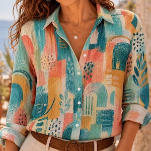 May include: A long-sleeve button-down shirt featuring an abstract print with brushstroke patterns in shades of teal, coral, yellow, and white. The shirt has a classic collar, a front button placket with white buttons, and cuffed sleeves.