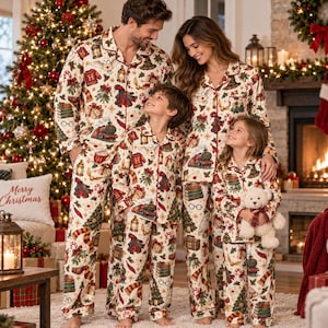 May include: A family wearing matching cream-coloured button-down pyjama sets featuring a festive pattern of trains, books, owls, and holiday greenery. The pyjamas have red piping along the collars, cuffs, and button plackets.