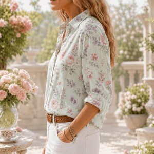 May include: A long-sleeved button-down shirt in a light mint green colour featuring a delicate floral pattern with pink and purple roses and small blossoms. The shirt has a classic collar, a front button placket, and sleeves rolled up at the cuffs.