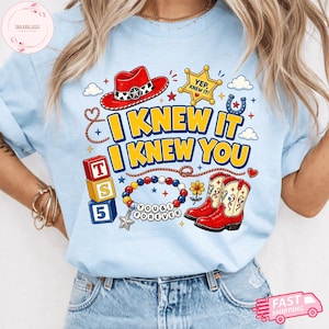 Pode incluir: Uma t-shirt azul-clara com uma estampa gr&aacute;fica de um chap&eacute;u de cowboy vermelho, uma estrela de xerife amarela com o texto YEP, KNEW IT, blocos empilhados TS 5, uma pulseira de contas com o texto YOU & I FOREVER e botas de cowboy vermelhas.