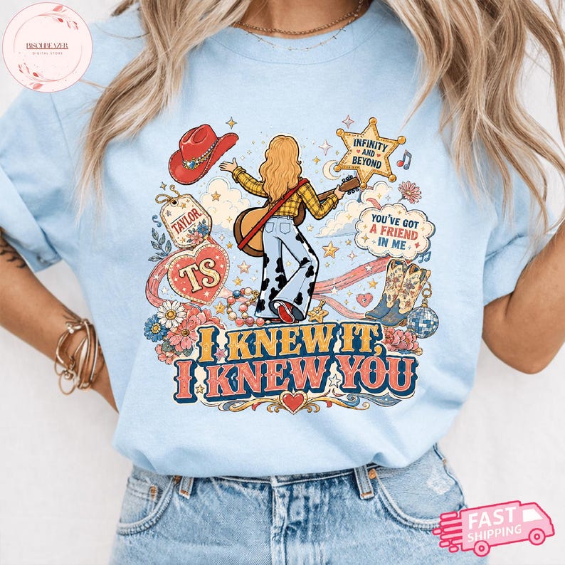 Może przedstawiać: Jasnoniebieski t-shirt z nadrukiem graficznym przedstawiającym osobę z długimi włosami grającą na gitarze, otoczoną czerwonym kowbojskim kapeluszem, gwiazdą, kwiatami, kulą dyskotekową i kowbojkami. Tekst: "TAYLOR", "TS", "INFINITY AND BEYOND", "YOU'VE GOT A FRIEND IN ME", "I KNEW IT, I KNEW YOU".