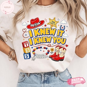 Pode incluir: Uma t-shirt cor de creme com uma estampa gr&aacute;fica de um chap&eacute;u de cowboy vermelho, uma estrela de xerife amarela com o texto YEP, KNEW IT!, blocos empilhados com T, S, 5, uma pulseira de contas com o texto YOU & I FOREVER e botas de cowboy vermelhas.