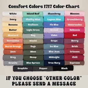 May include: A Comfort Colors 1717 color chart displaying folded t-shirts in various shades including white, ivory, banana, butter, mustard, terracotta, burnt orange, yam, grey, granite, graphite, island reef, chalky mint, seafoam, light green, bay, khaki, sage, moss, hemp, blue spruce, pepper, chambray, lagoon blue, flo blue, orchid, violet, grape, ice blue, blue jean, midnight, true navy, blossom, crunchberry, watermelon, heliconia, red, berry, brick, crimson, chili, espresso, and black.