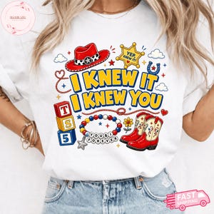 Pode incluir: Uma t-shirt branca com uma estampa gr&aacute;fica que inclui um chap&eacute;u de cowboy vermelho, uma estrela de xerife amarela com o texto YEP, KNEW IT!, blocos empilhados T, S, 5, uma pulseira de contas com o texto YOU & I FOREVER e botas vermelhas.