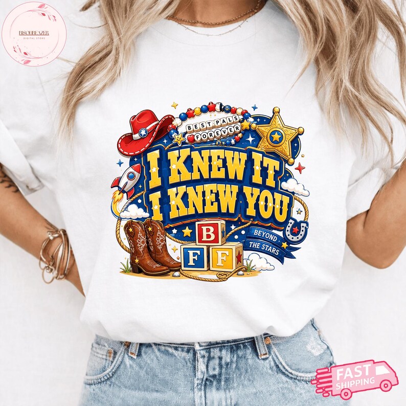 May include: A white t-shirt featuring a colorful graphic with the text I KNEW IT I KNEW YOU, BEST PALS FOREVER, and BEYOND THE STARS. The design includes a red cowboy hat, a gold sheriff star, a rocket, brown cowboy boots, and alphabet blocks B F F.