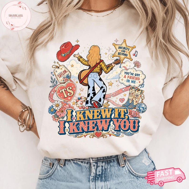 Może przedstawiać: Kremowy t-shirt z nadrukiem graficznym przedstawiającym osobę z długimi blond włosami grającą na gitarze, otoczoną czerwonym kowbojskim kapeluszem, gwiazdą, kwiatami i butami. Tekst brzmi "TAYLOR", "TS", "INFINITY AND BEYOND", "YOU'VE GOT A FRIEND IN ME", "I KNEW IT, I KNEW YOU".