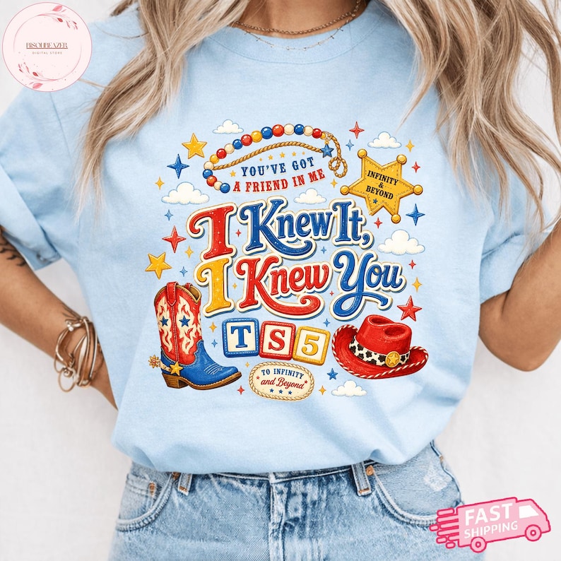 May include: A light blue t-shirt featuring a graphic print with the text "You've Got A Friend In Me", "I Knew It, I Knew You", "TS5", and "To Infinity and Beyond". The design includes a cowboy boot, a red hat, a sheriff star, and colorful beads.