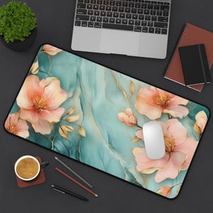 May include: A teal and gold marble-effect mousepad with a floral design featuring pink flowers and gold accents.