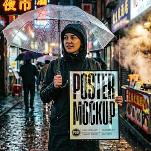Könnte beinhalten: Eine Person hält einen Poster-Mockup in einer regnerischen Straßenszene. Das Poster zeigt die Worte "POSTER MOCKUP" in großen schwarzen Buchstaben. Das Poster enthält auch den Text "PSD FORMAT", "4K DISPLAY", "SMART OBJET" und "EAY EDIT".