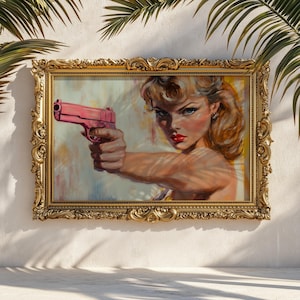 May include: A framed artwork depicting a woman with blonde hair and red lipstick aiming a pink handgun. The painting is set in a gold ornate frame, with palm fronds casting shadows on the white wall behind it.