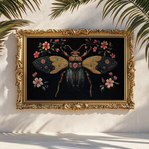 May include: A framed artwork featuring a detailed illustration of a jeweled beetle with gold and teal accents, set against a black background. Pink flowers and gold frame complete the design. The artwork is displayed on a white wall.