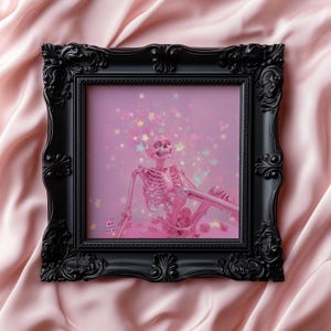 May include: A pink skeleton sits in a relaxed pose against a pink background with sparkling stars. The skeleton is framed in a black ornate frame.