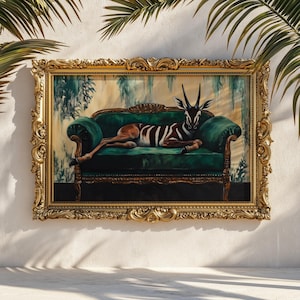 May include: A framed artwork featuring a gazelle reclining on a green velvet sofa. The gazelle has brown and white striped markings. The ornate gold frame surrounds the painting, which is set against a backdrop of a white wall and palm fronds.