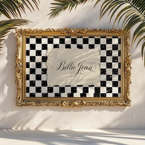 Puede incluir: Una obra de arte enmarcada en un marco dorado ornamentado, con un patrón de cuadros blanco y negro. El papel crema dentro del marco muestra el texto en cursiva "Billie Jean". Se ven hojas de palmera en el fondo.