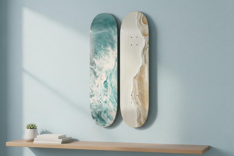 May include: Two skateboard decks mounted vertically. The left deck features a swirling teal, blue, and white abstract pattern resembling ocean waves. The right deck displays a smooth, light beige and cream marbled design with a textured appearance.