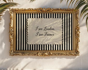 May include: Ornate gold framed artwork with a black and white striped background. A cream-colored paper with scalloped edges is centered, displaying the text "I see London, I see France". Palm fronds are visible in the background.