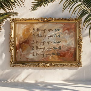 May include: An ornate, gold-framed artwork with an abstract, textured background in shades of brown and beige. The artwork features handwritten text: "5 things you see, 4 things you feel, 3 things you hear, 2 things you smell, 1 thing you taste."