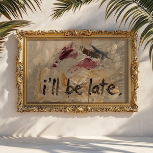 May include: An ornate gold framed painting with the text "i'll be late." The artwork features abstract brushstrokes in shades of beige, burgundy, and gray. The painting is displayed against a white wall with palm fronds.