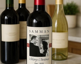 May include: Several wine bottles with different colored foil tops. The front bottle has a red foil top and a label with a black and white photo of a couple, the word "SAMMAN", and "Merry Christmas Dec 2018 100% LOVE".