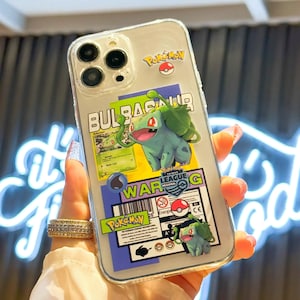 Może przedstawiać: Przezroczyste etui na telefon z zielonym i czarnym wzorem Pokemon Bulbasaur. Etui zawiera tekst "Bulbasaur War G" i logo Pokemon League.