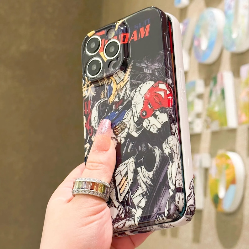 Puede incluir: Una funda transparente para tel&eacute;fono con una ilustraci&oacute;n de anime colorida de un robot con el texto "Gundam" impreso en ella.